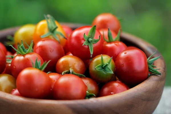 Pomodori ciliegia maturi in un piatto di legno Fotografia Stock