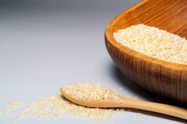 Gri izole arkaplanda beyaz susam tohumlarını veya kimyonları kaşıklarla kapat