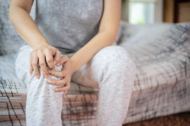 Diz çevresindeki kemik ağrısı ya da dizler, kızın eli diz bölgesini tutuyor..