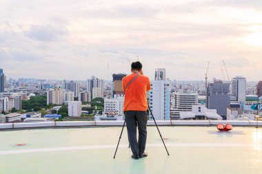 Tripodu kullanarak fotoğraf çek. Gökyüzünde fotoğraf çekme niyetinde olan fotoğrafçı gökdelen inşaatı