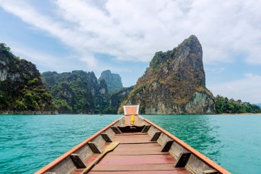 Tayland 'daki Rajjaprabha Barajı' nda tekne yolculuğu. Uçsuz bucaksız göl ormanlarının görkemli atmosferi. Özellikle de kireçtaşı dağlarının güzelliği ve gölün berrak sularıyla..