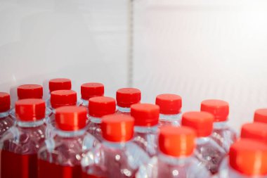Beyaz buzdolabında içme suyu bulunan saydam plastik şişeler. Sıcak yaz gününde içmek için buzdolabında maden suyu deposu. Şişe kapağı ve kırmızı etiket