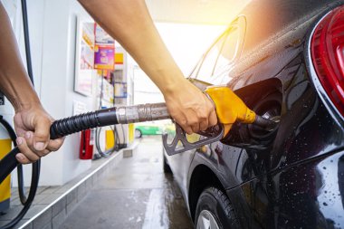 Refuel cars at the fuel pump. The driver hands, refuel and pump the car's gasoline with fuel at the petrol station. On a day of heavy rain