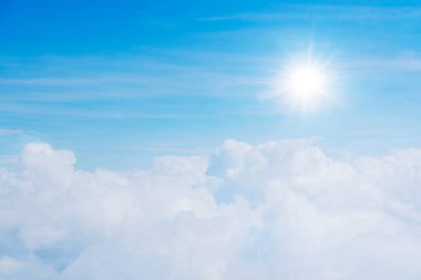 Gökyüzü bulutlarla doludur, hem küçük hem de büyük, güneş parıldıyor. Atmosfer uçakta..