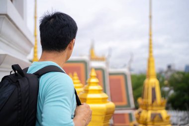 Sırt çantalı genç bir Asyalı yaz tatilinde Bangkok 'taki Tayland tapınaklarını ziyaret etmeye bayılır..