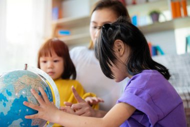 Mutluluk, Asyalı aile, anne ve çocuklar haritada dünya seyahati ülkesini buluyor. Tüm üyelerle aile aktivitesi için bir gezi planlamak.