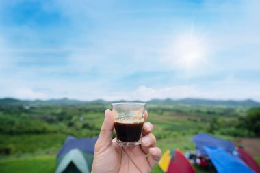 Elinde espresso fincanı tutan bir adam güzel doğal dağ manzarasına bakıyor. Sabahları kahve iç.