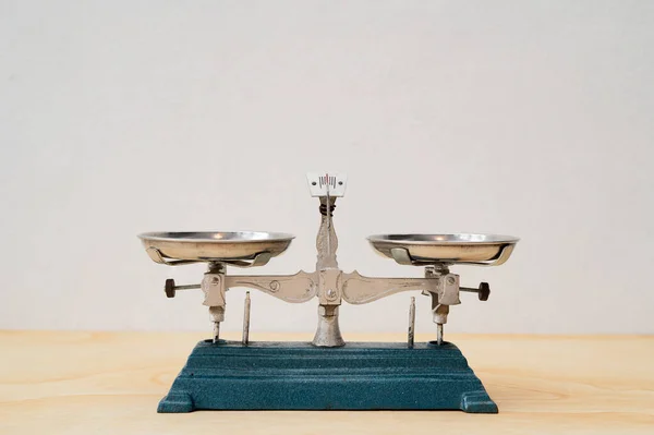 Antique vintage balance scales, Cast iron is placed on a wooden table on the background of a white wall.