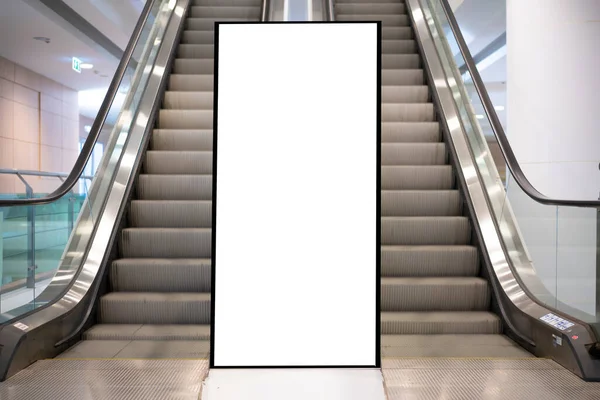 A billboard mounted in the middle of the escalator area, a white billboard background.