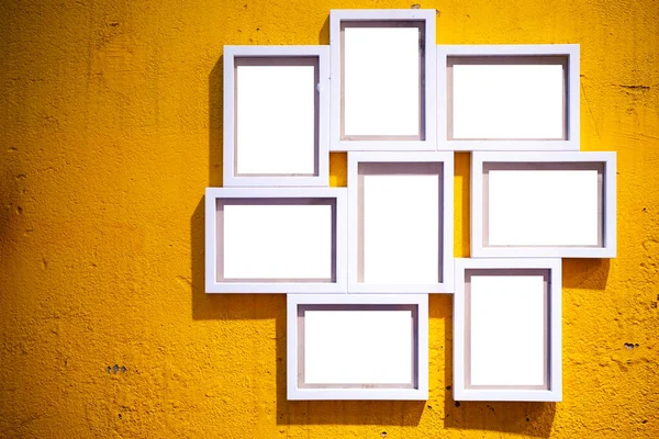 Photo frame on wall. A blank white picture frame hanging on an old yellow plaster wall