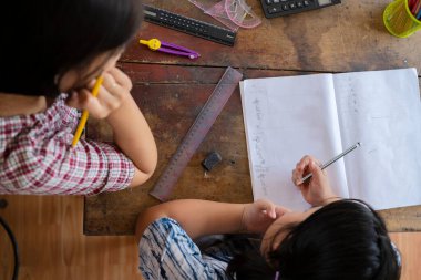 Üst tabaka, sevimli bir Asyalı kız öğrenci öğretmeniyle birlikte çalışıyor, öğretmene bir soru soruyor..