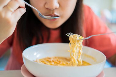 Yemek çubuğu ve kase kullanarak lezzetli sıcak ve baharatlı erişte yiyen Asyalı kadını kapatın. Masada yemek yemek.