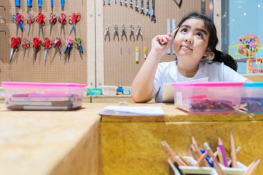 Masalarında el sanatları yapan mutlu çocuklar icat edeceği şeyi düşünüyordu..