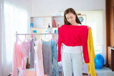 Kadınlar giyecek, giyecek, moda, tarz ve insan konsepti seçer. Mutlu kadın evde kıyafet seçer.