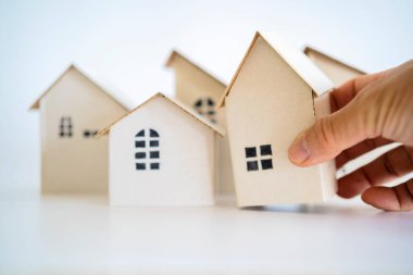 Beyaz kağıt ev modeli emlakçıları olan bir adam ev, mülk, sigorta ve güvenlik teklif ediyor. Konsept evler al ve kirala Beyaz arka plan