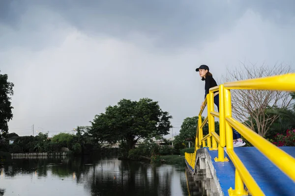 公園の湖の上の橋の上でストレッチ練習をするランナー — ストック写真
