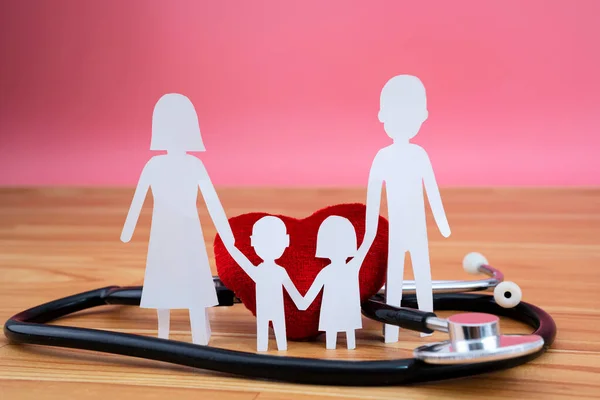 Aile için sağlık sigortası yaptırın. Stetoskop, ailenin kalbi ahşap arka planda