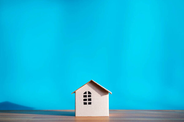 White paper house design isolated on blue background, shadows showing warmth. The empty space can include advertising text.