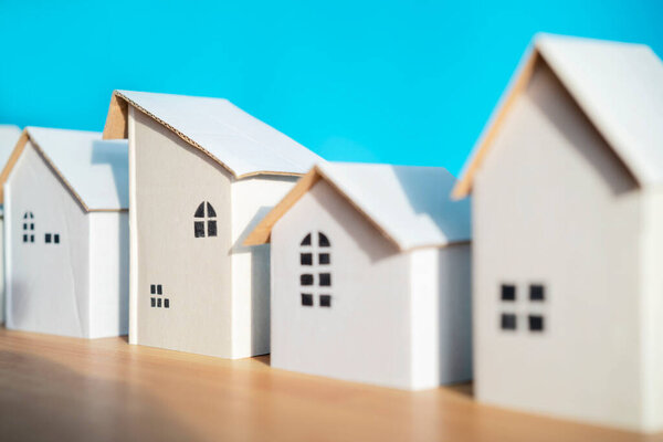 Дизайн белого бумажного дома расположен отдельно на синем фоне, тени, показывающие тепло