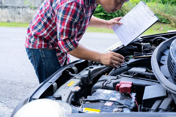 Services car engine machine concept, Automobile mechanic repairman checking a car engine with inspecting writing to the clipboard the checklist for repair machine, car service and maintenance.