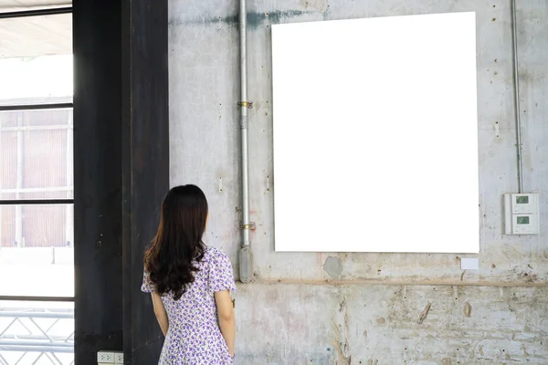 白い壁のアートギャラリーの上に立って空の絵のフレームを見ている女性 — ストック写真