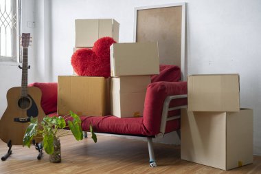 Moving day concept, cardboard carton boxes stack with household belongings in modern house living room, packed containers on floor in new home, relocation, renovation, removals and delivery service clipart