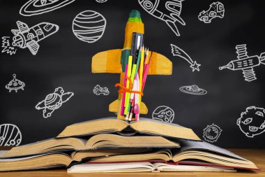 Eğitim konsepti ve okula dönüş. Sınıftaki uzay nesnelerini gösteren bir karton roket, tahtanın önüne yerleştirilmiş..