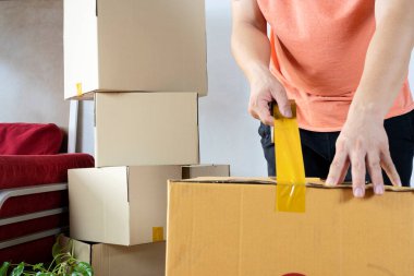 Ev taşıma konsepti. Karton kutu paketleyen bir adamın yeni bir eve taşınması.