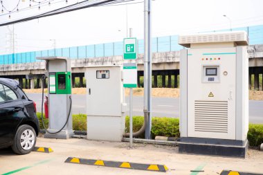 Elektrikli araba, şehir caddesinde elektrikli araba şarj istasyonuyla park yerinde şarj oluyor. Elektrikli arabalar hazır bekliyor..