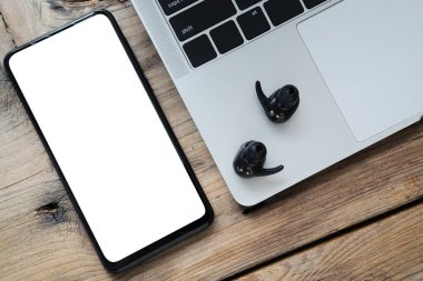 Dizüstü bilgisayarlar, mobil aksesuarlar bant siyah kablosuz kulaklıklar, kablosuz kulaklıklar android mobil boş tahta arka plan.