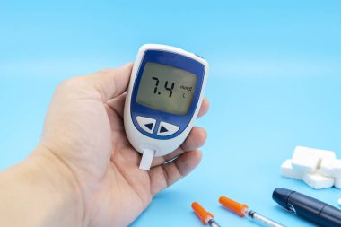 Bir adam mavi arka planda şeker için kan testi yapar. Metin için boşluk