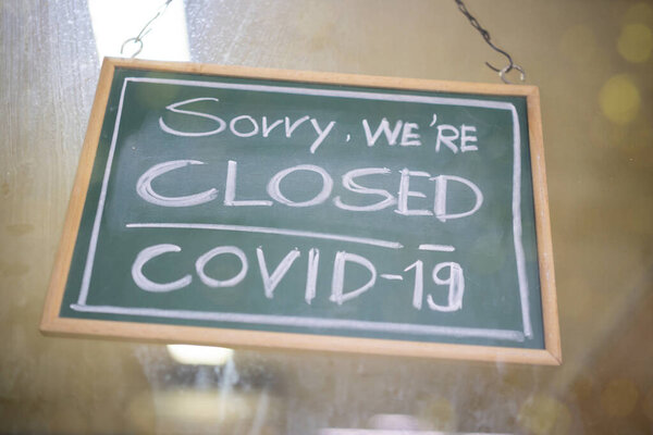 Временно закрытый знак Ковид-19 в деятельности малого бизнеса. Сообщение о карантинных мерах. Закрыть на красном закрытом плакате в окне магазина коронавируса.