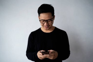 Modaya uygun genç sakallı adamın şık kıyafetler giymesine sevindim. Moda tarzı var, arkadaşlarıyla mesajlaşmaktan mutlu, elektronik aletler üzerinde ücretsiz internet bağlantısı kullanıyor.