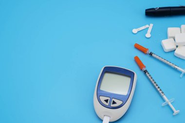 Mavi arka planda test şeridi olan glukometre. Metin için boşluk, seçici odak