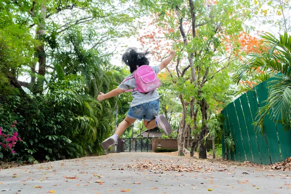 学校に戻る かわいいですアジアの子供の女の子とともにバックパックランニング ジャンプし 楽しいと学校に行きます — ストック写真