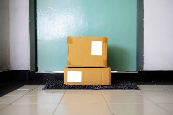 玄関近くのドアマットに小包を配達し 木製のドアの外に小包 — ストック写真