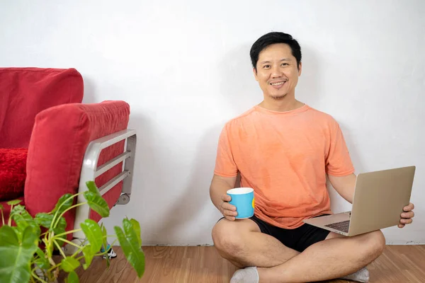 Hombre Barbudo Sonriente Usando Portátil Casa Mientras Está Sentado Suelo —  Fotos de Stock