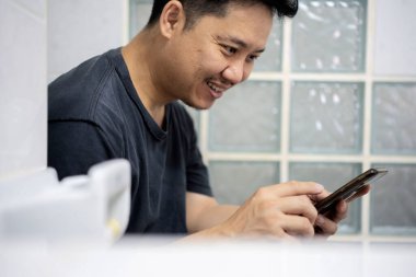 Adam tuvalet akıllı telefon kullanmak, internet sörf. Tuvalet telefonu tutan erkek elleri yakın çekim.