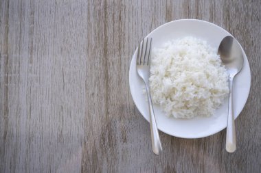 Tayland kokulu yasemin pilavı kahverengi ahşap bir masada beyaz bir tabakta servis edilir. Tayland kökenli pirinçler pandan yapraklarına benzer bir kokuya sahiptir.