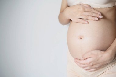 Genç hamile kadın ellerini şişmiş karnında tutuyor. Aşk konsepti. Kopyalama alanı ile yatay