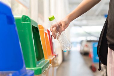 Atık ayıklama istasyonunda boş plastik şişeyi geri dönüşüm kutusuna koymak. Sürdürülebilirlik, çevre dostu yaşam tarzı, plastik azaltma, çevre sorumluluğu ve temiz şehir konsepti.