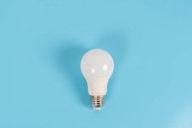 Fotokopi alanı ile mavi zemin üzerine kurulmuş tek LED ampul, enerji tasarrufu, modern ışıklandırma, minimal tasarım, elektrik, yenilik ve ev hizmetini sembolize ediyor.
