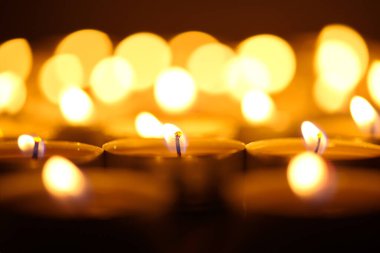 Mum yakıyorum. Yüzeyin derinliği. Geceleri bir sürü Noel mumu yanıyor. Soyut mum arkaplanı. Karanlık arka planda parlayan bir sürü mum alevi var. Yakın plan. Boş alan.