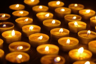 Mum yakıyorum. Yüzeyin derinliği. Geceleri bir sürü Noel mumu yanıyor. Soyut mum arkaplanı. Karanlık arka planda parlayan bir sürü mum alevi var. Yakın plan. Boş alan.