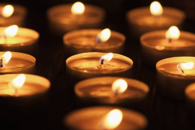 Mum yakıyorum. Yüzeyin derinliği. Geceleri bir sürü Noel mumu yanıyor. Soyut mum arkaplanı. Karanlık arka planda parlayan bir sürü mum alevi var. Yakın plan. Boş alan.