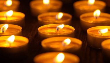 Mum yakıyorum. Yüzeyin derinliği. Geceleri bir sürü Noel mumu yanıyor. Soyut mum arkaplanı. Karanlık arka planda parlayan bir sürü mum alevi var. Yakın plan. Boş alan.