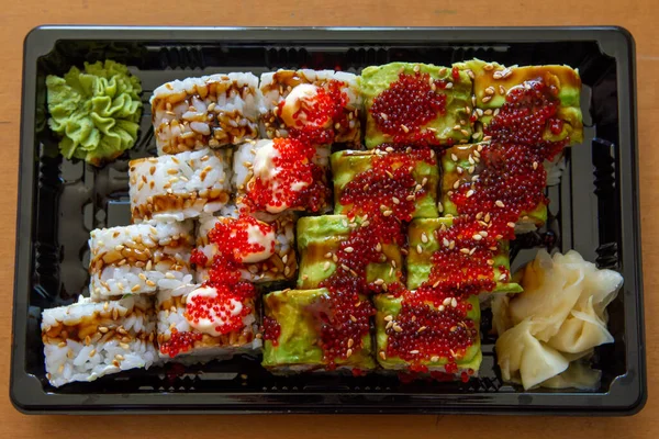 Siyah bir tabakta zencefil ve wasabi ile suşi rulolarının üst görüntüsü