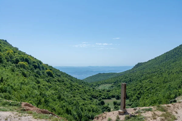 Dağlar arasında yeşil ağaçlarla kaplı şehir silüeti