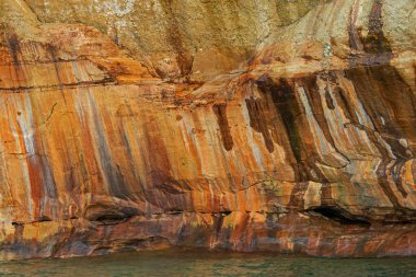 Superior Gölü 'nün aşınmış kumtaşı kıyı şeridi boyunca uzanan mineral lekeli uçurumun soyut manzarası, Resimli Kayalar Ulusal Lakeshore, Michigans Yukarı Yarımadası, ABD