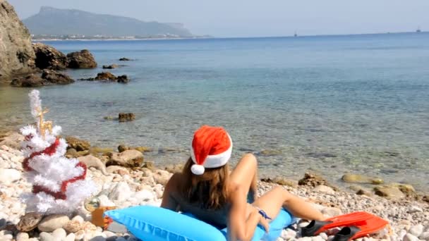 Young woman relaxing on the beach with christmas tree — Stock Video